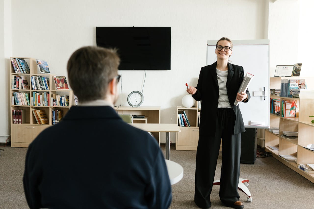 pexels-photo-6981024 Businesswoman giving presentation in office with bookshelves and clock.